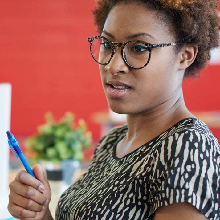 Lady wearing glasses, holding a pen, representing the Purple House Clinic's Consultation & Support Services.